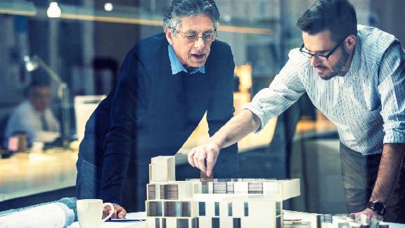 Two men discussing about building plan.