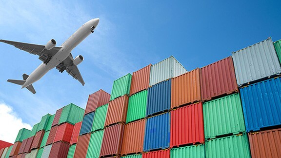 Upwards view of a stack of cargo containers with a cargo airplane in flight