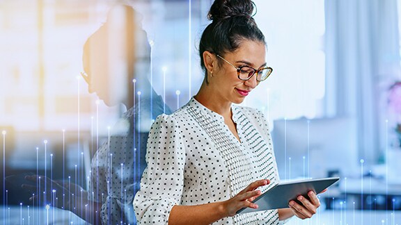 A woman wearing glasses scroling on a tablet and smiling