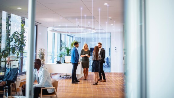 A group of colleagues in conversation at an office lobby