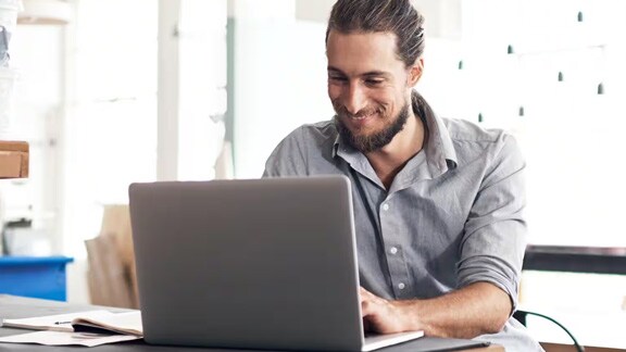 Man smiling and working on a laptop