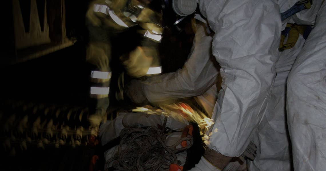 People in protective equipment working with a bag on the floor