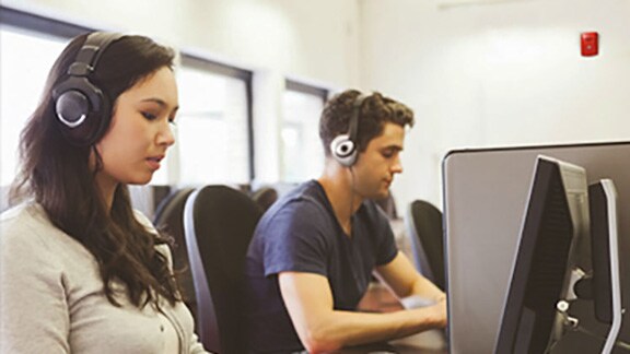 A man and woman working in office while wearing headphone