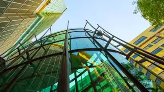 Frog's-eye view of glass buildings surrounded by trees