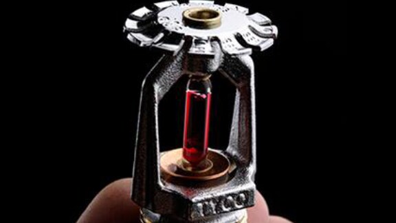 Close up of a hand holding a fire sprinkler