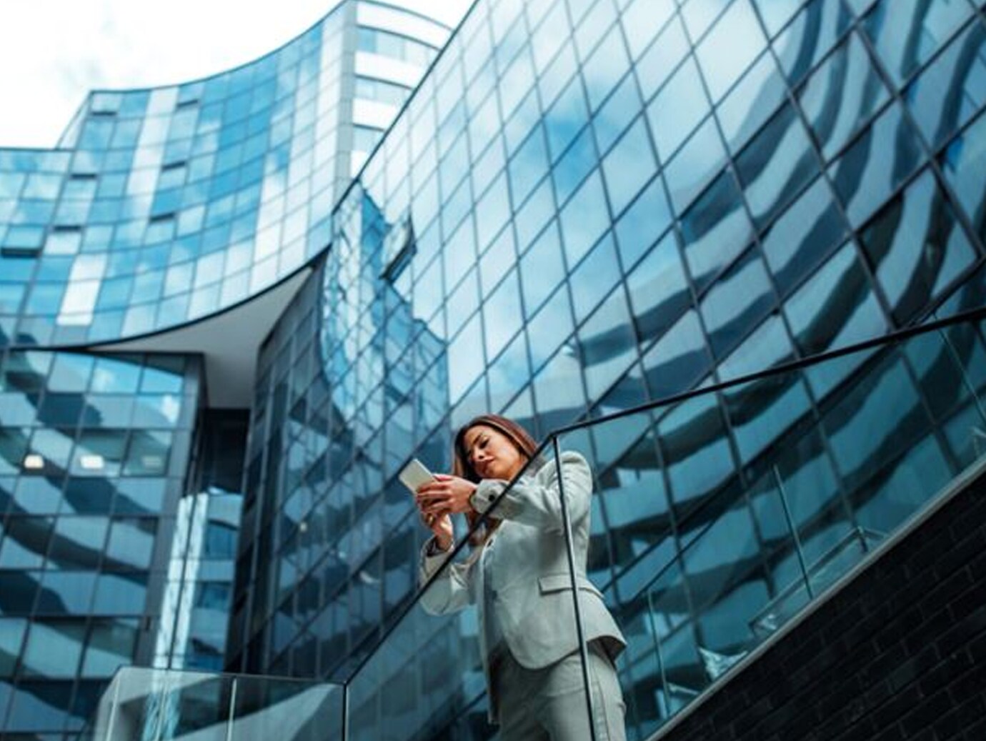 Low-angle view of a woman using a smartphone outside an office building