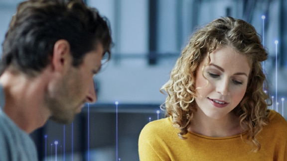 A man and a woman in conversation at work, with OpenBlue graphics in the background