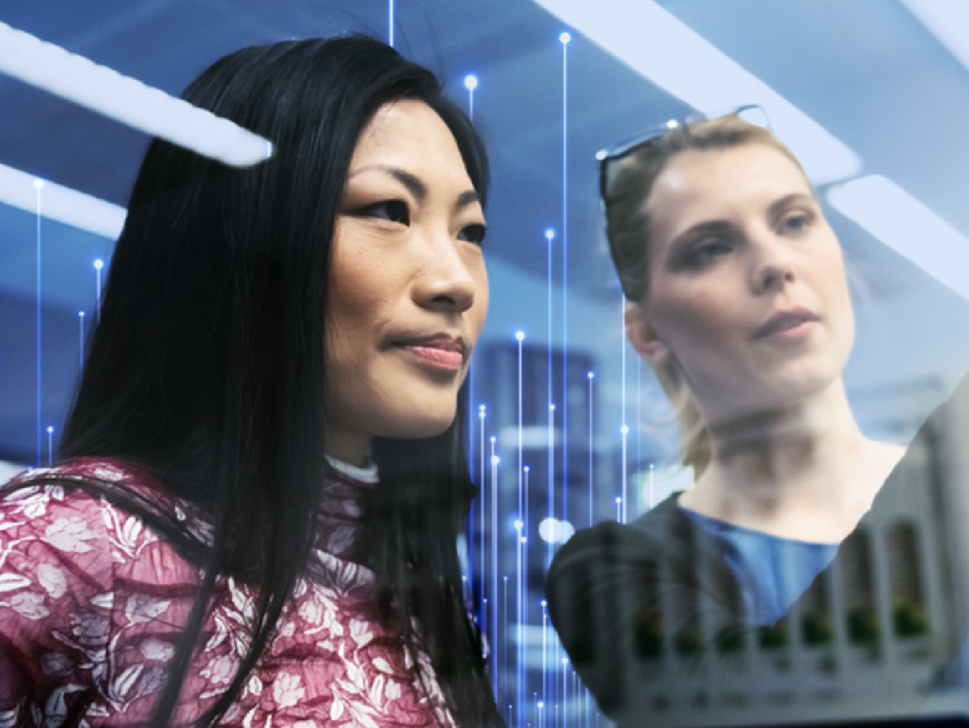 Two women looking into the distance as one of them points at something, overlaid with OpenBlue graphics