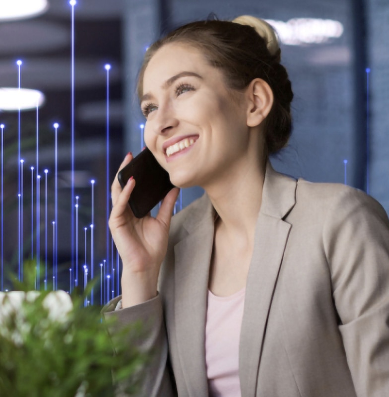 A woman smiling while talking on a mobile phone, with a row of plants by her and OpenBlue graphics in the background