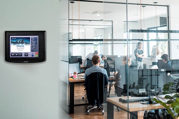 A fire control panel on a wall next to an office with people working inside