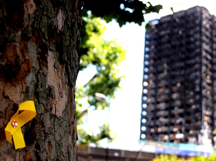 Yellow ribbon nailed on a tree to symbolise fire safety with a blurred high rise building in the background