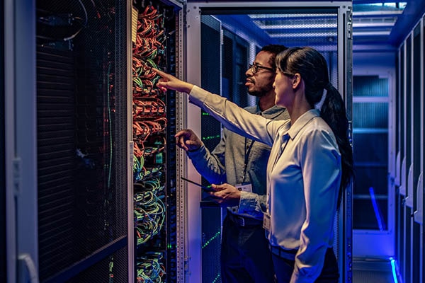 Two people in front of a data centre rack