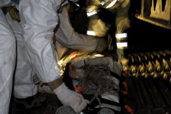 People in protective equipment working with a bag on the floor