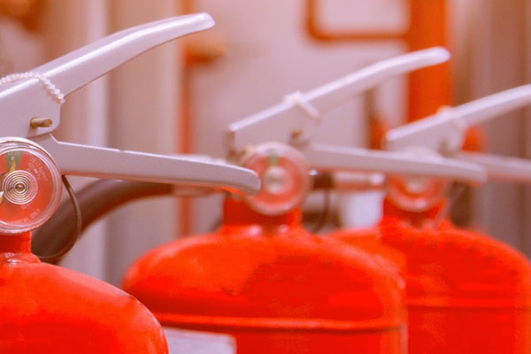 A clipboard and three fire extinguishers in a line