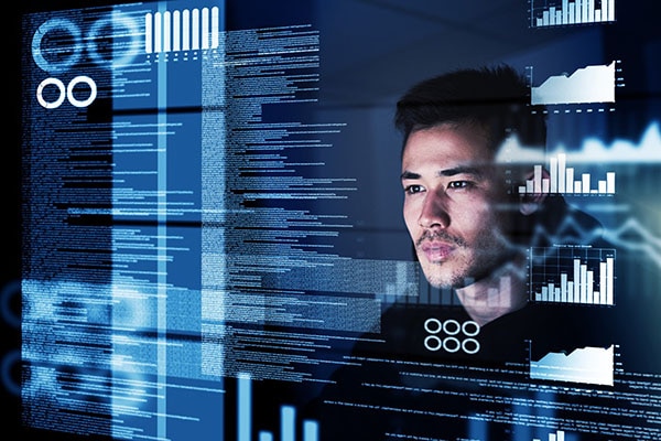 A man looking at a glass screen with text and graphs